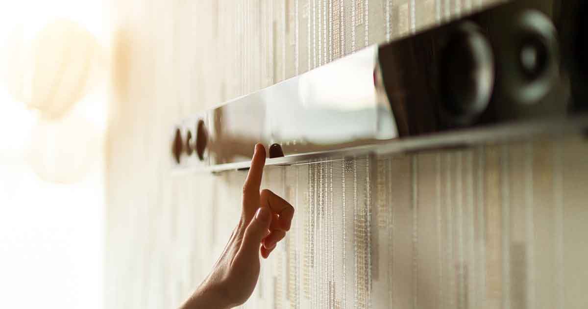 Hand adjusting sound bar speaker on the wall